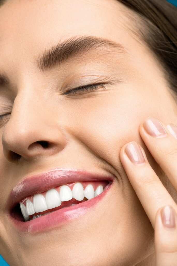 Close-up Photo of Woman With Pink Lipstick Smiling with Her Eyes Closed